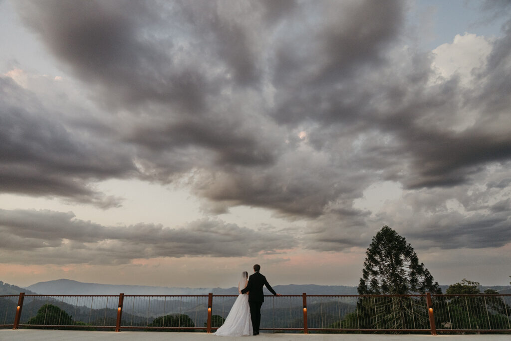 Bride and groom overlooking Sunshine Coast Hinterland views from the deck at Maleny Country Estate